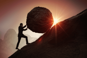 Salesperson pushing large rock up a mountain.